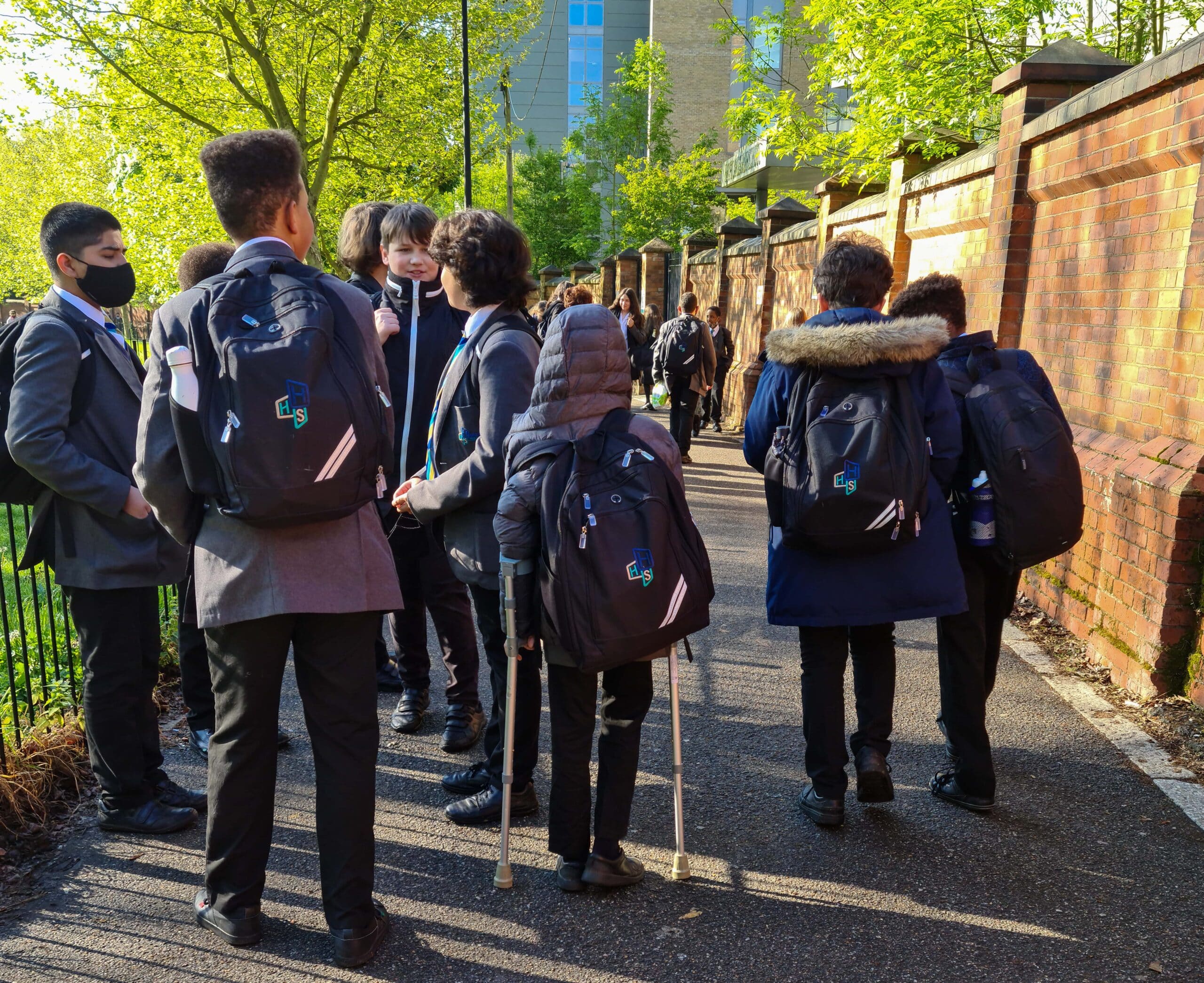 A group of secondary school students in uniform gather outside on a sunny day, symbolizing the vibrant school environment associated with Secondary Teacher jobs in Peterborough
